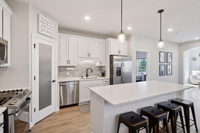 kitchen featuring backsplash, a kitchen bar, arched walkways, a sink, and stainless steel appliances