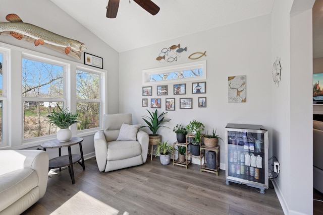 living area featuring baseboards, ceiling fan, wood finished floors, and high vaulted ceiling