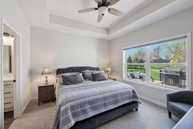 bedroom with ceiling fan, baseboards, light colored carpet, and a tray ceiling