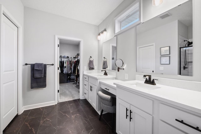 full bath with visible vents, marble finish floor, baseboards, two vanities, and a sink