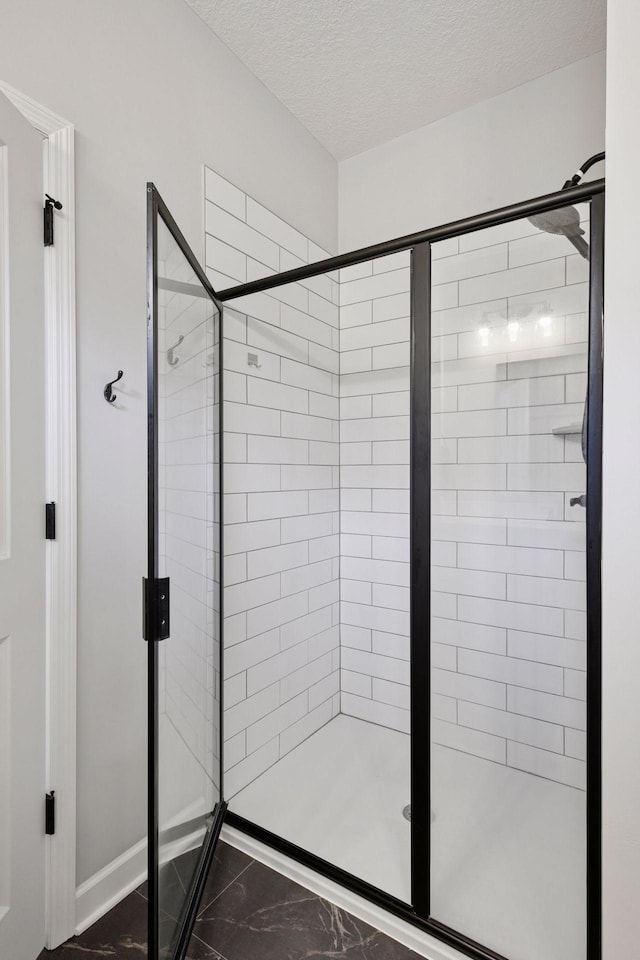 full bath featuring a shower stall, a textured ceiling, and marble finish floor