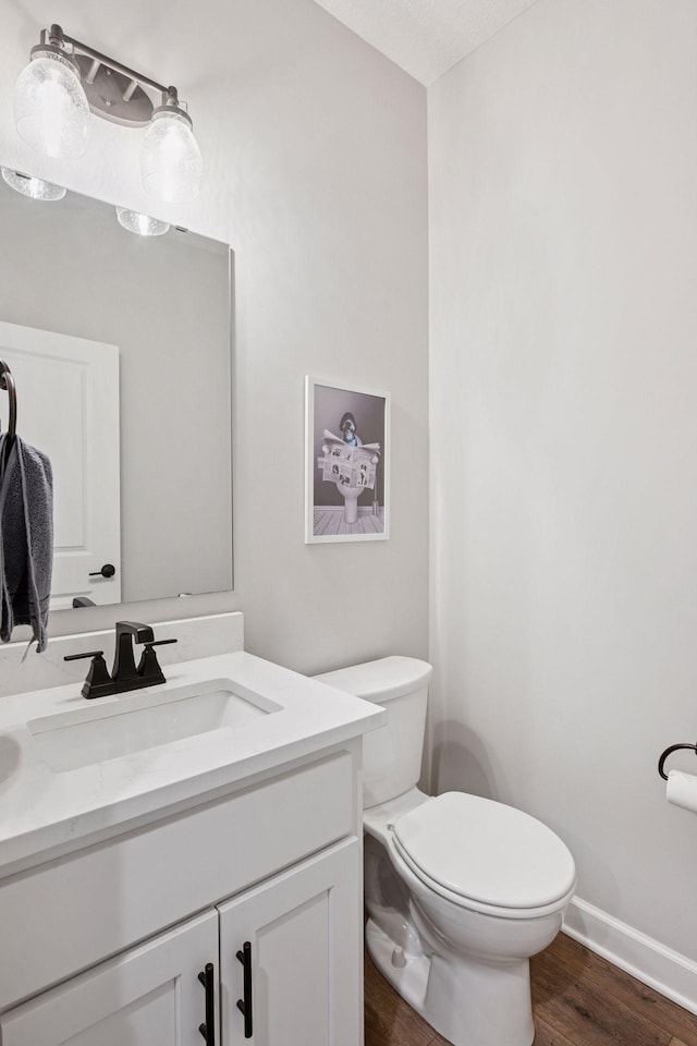 bathroom with toilet, baseboards, wood finished floors, and vanity
