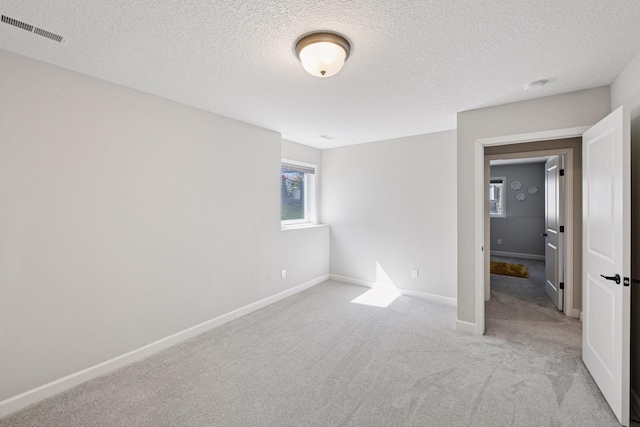 unfurnished bedroom with carpet floors, baseboards, a textured ceiling, and visible vents
