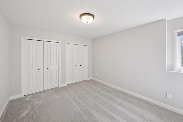 1519 80th St, Victoria, MN 55386 - unfurnished bedroom with multiple closets, carpet floors, a textured ceiling, and baseboards