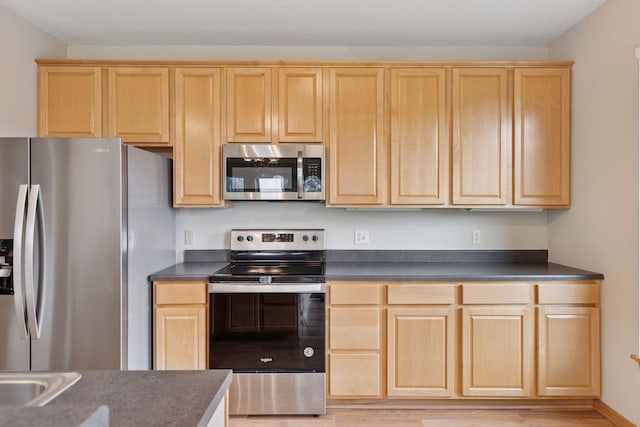645 1st St Unit 411, Minneapolis, MN 55401 - kitchen featuring stainless steel appliances, light brown cabinetry, dark countertops, and light wood-type flooring