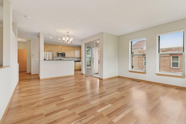 645 1st St Unit 411, Minneapolis, MN 55401 - unfurnished living room featuring a chandelier, healthy amount of natural light, and light wood-type flooring
