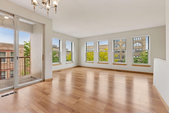 645 1st St Unit 411, Minneapolis, MN 55401 - spare room with a chandelier, light wood-style floors, and baseboards
