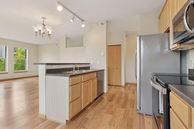 645 1st St Unit 411, Minneapolis, MN 55401 - kitchen with stainless steel appliances, light brown cabinets, a sink, dark countertops, and light wood-style flooring