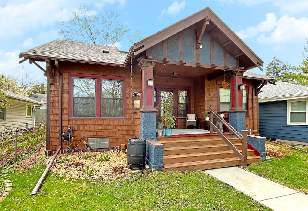 bungalow-style house with roof with shingles, fence, and a front yard