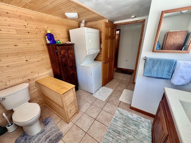4832 Ambassador Point Ct, Leiding Twp, MN 55771 - bathroom featuring stacked washer / drying machine, wooden walls, tile patterned flooring, baseboards, and toilet