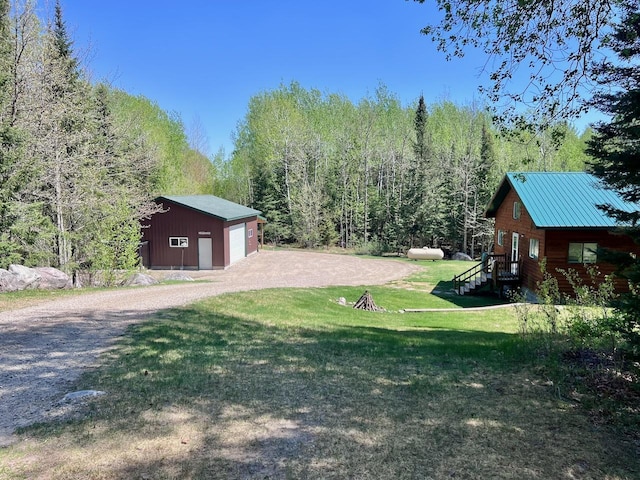 4832 Ambassador Point Ct, Leiding Twp, MN 55771 - view of green lawn with a detached garage, an outbuilding, a wooded view, and dirt driveway