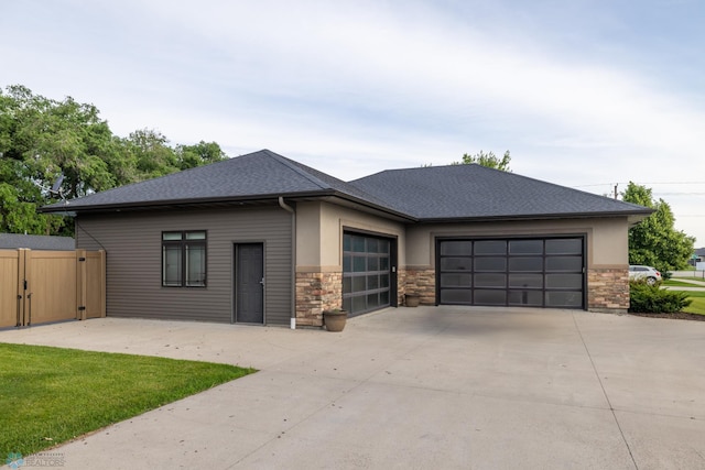 4109 66th St S, West Fargo, ND 58104 - view of front facade featuring an attached garage, driveway, stone siding, a shingled roof, and stucco siding