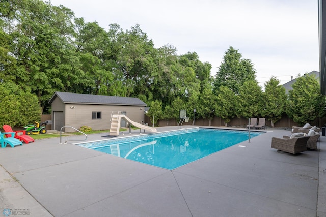 4109 66th St S, West Fargo, ND 58104 - view of swimming pool with a water slide, an outdoor structure, a patio, and view of scattered trees