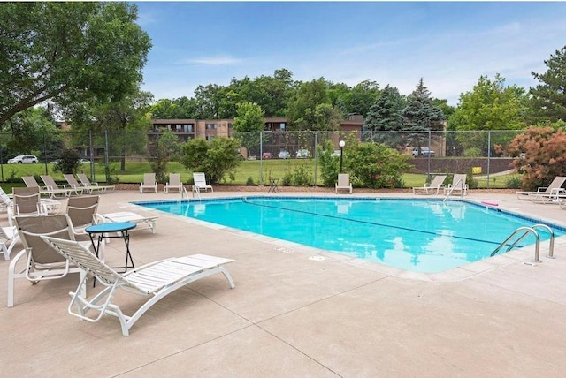 community pool with a patio area and fence