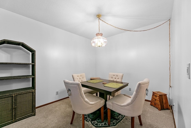 carpeted dining area with a notable chandelier and baseboards