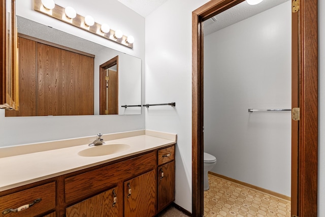 bathroom featuring tile patterned floors, vanity, baseboards, and toilet