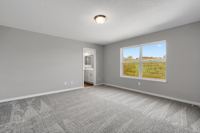15676 71st St NE, Otsego, MN 55330 - unfurnished bedroom featuring baseboards, carpet floors, ensuite bath, and a textured ceiling