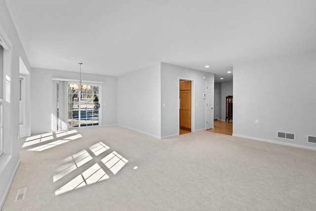 unfurnished living room featuring light colored carpet, a chandelier, recessed lighting, baseboards, and visible vents