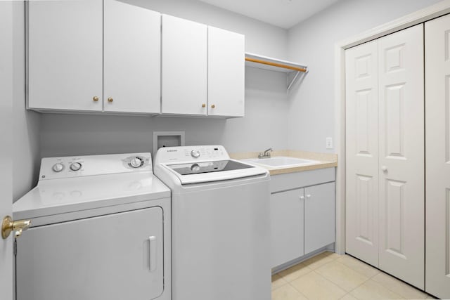 washroom featuring cabinet space, light tile patterned floors, a sink, and washer and clothes dryer