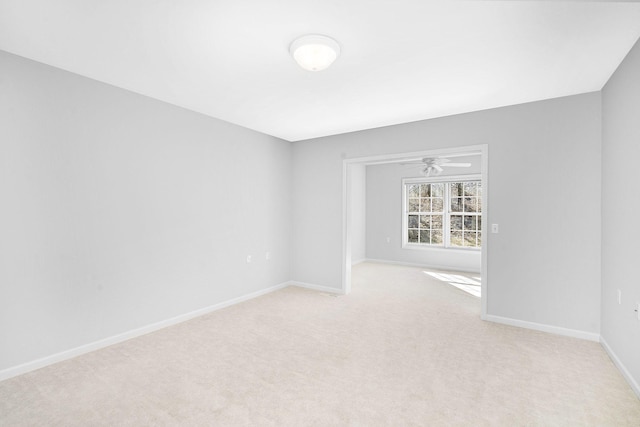 spare room featuring baseboards, light carpet, and a ceiling fan
