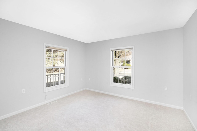 unfurnished room with baseboards, light colored carpet, and plenty of natural light