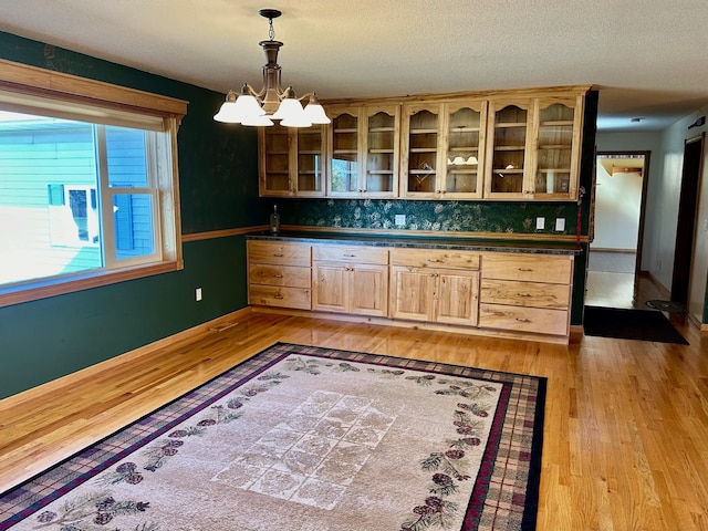16335 County Road 2, Brainerd, MN 56401 - kitchen featuring light brown cabinets, light wood-style floors, dark countertops, a chandelier, and glass insert cabinets