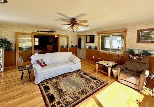 16335 County Road 2, Brainerd, MN 56401 - living room featuring a wainscoted wall, light wood-style floors, ceiling fan, wooden walls, and wallpapered walls