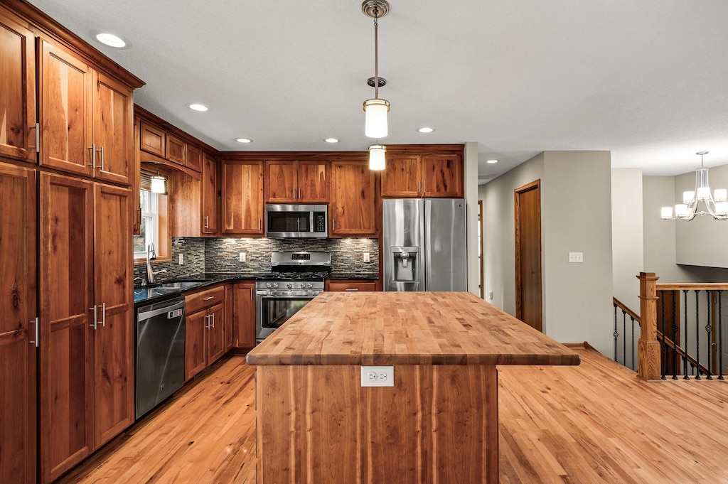 kitchen with a notable chandelier, tasteful backsplash, appliances with stainless steel finishes, wooden counters, and decorative light fixtures