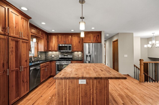 kitchen with a notable chandelier, tasteful backsplash, appliances with stainless steel finishes, wooden counters, and decorative light fixtures