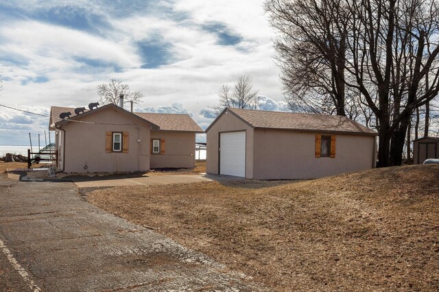 5591 Wildwood Ave, Isle, MN 56342 - view of side of property with an outbuilding, stucco siding, and driveway