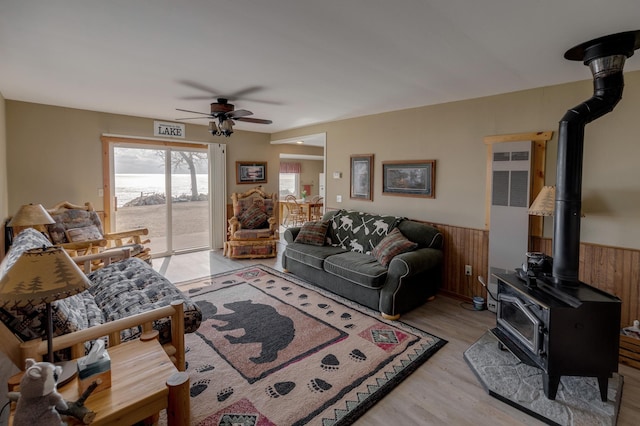 5591 Wildwood Ave, Isle, MN 56342 - living area featuring a wood stove, a ceiling fan, a wainscoted wall, light wood finished floors, and a heating unit