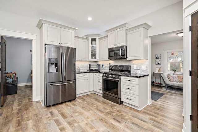5234 Grand Ave, White Bear Twp, MN 55110 - kitchen featuring dark countertops, appliances with stainless steel finishes, light wood-style floors, and decorative backsplash