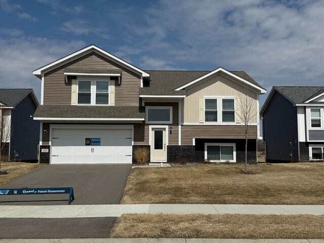 view of front facade featuring aphalt driveway, a shingled roof, board and batten siding, and an attached garage