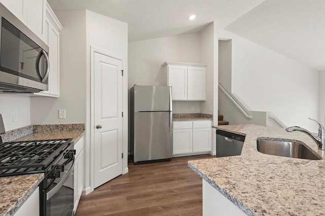 kitchen with a sink, dark wood finished floors, white cabinetry, vaulted ceiling, and stainless steel appliances