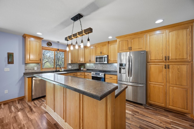 kitchen featuring appliances with stainless steel finishes, a sink, dark countertops, dark wood-style floors, and backsplash
