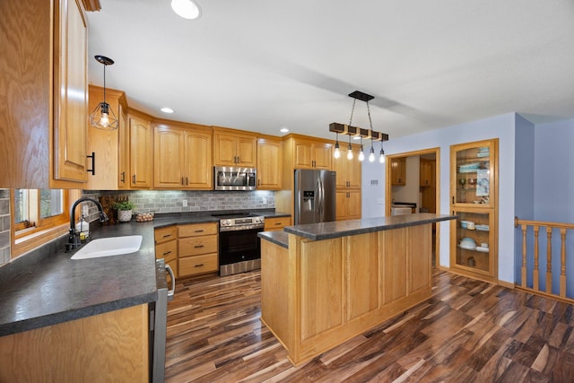 kitchen featuring appliances with stainless steel finishes, a sink, dark countertops, dark wood-type flooring, and decorative backsplash