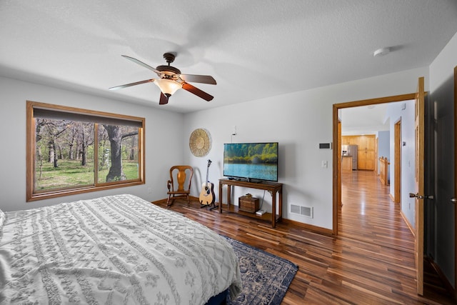bedroom featuring wood finished floors, baseboards, a textured ceiling, and a ceiling fan