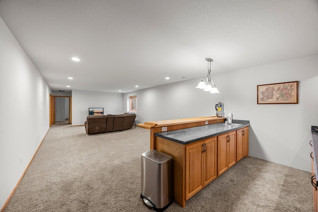 kitchen featuring light colored carpet, recessed lighting, a peninsula, dark countertops, and brown cabinets