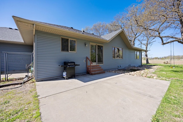 back of house with entry steps, a patio area, and a shingled roof