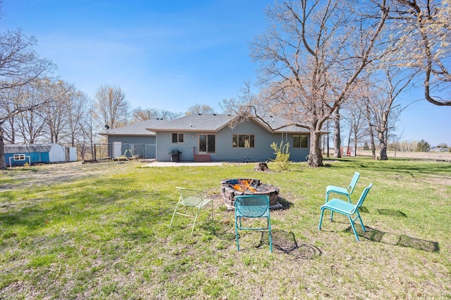 back of property featuring a fire pit, a shed, an outbuilding, and a patio