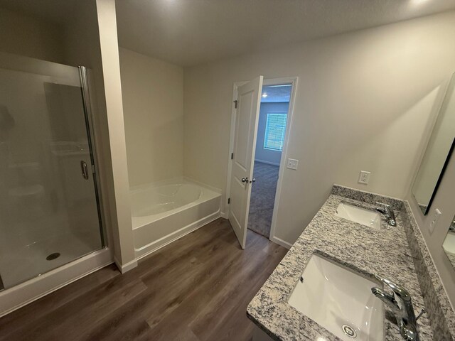 full bathroom featuring a sink, a shower stall, double vanity, and wood finished floors