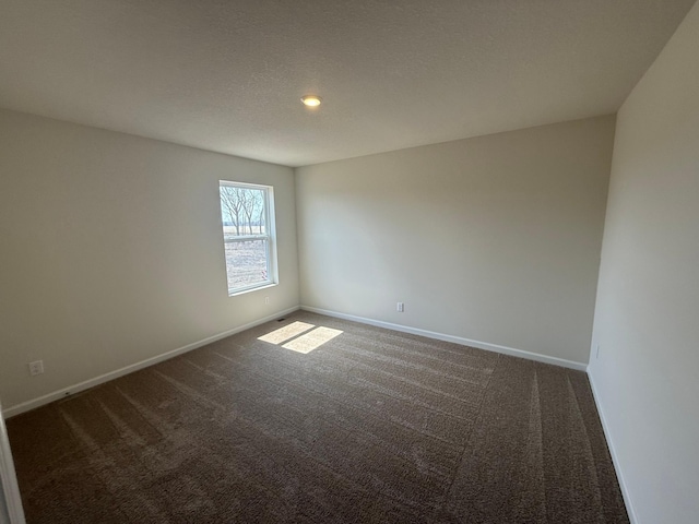 unfurnished room featuring baseboards and dark colored carpet