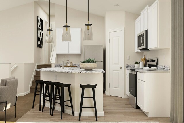 kitchen featuring light wood-style flooring, stainless steel appliances, white cabinetry, decorative light fixtures, and a breakfast bar area