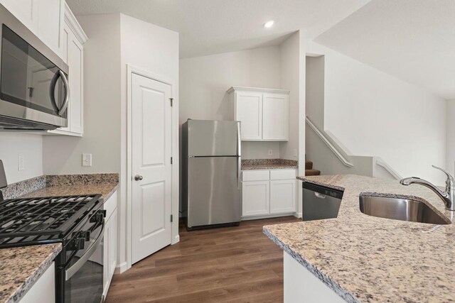 kitchen with vaulted ceiling, a sink, white cabinetry, appliances with stainless steel finishes, and dark wood finished floors