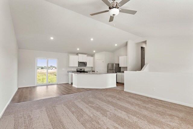 unfurnished living room with baseboards, ceiling fan, recessed lighting, vaulted ceiling, and light colored carpet