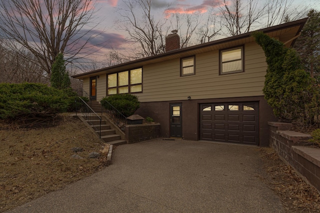 view of front of house featuring a chimney, driveway, and an attached garage