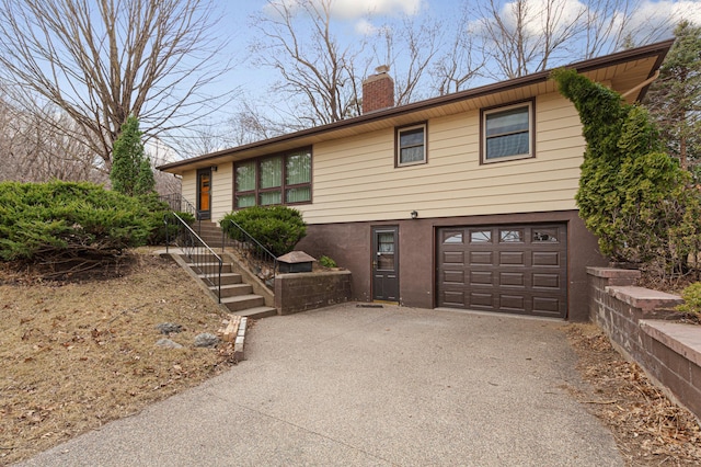 view of front facade with driveway, a garage, and a chimney