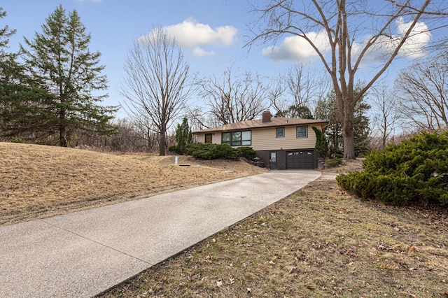 view of front of home with driveway, an attached garage, and a chimney