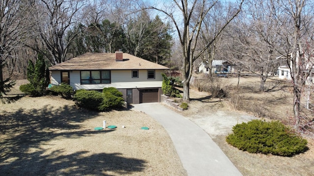 view of front of house with concrete driveway, a garage, and a chimney