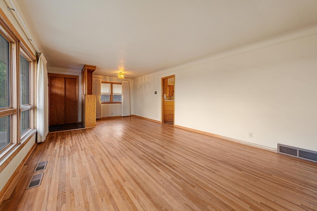 unfurnished living room with baseboards, visible vents, and light wood-type flooring